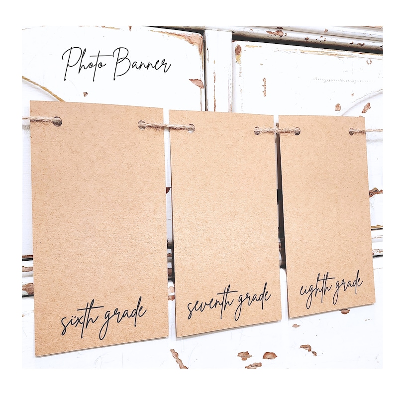 May include: Photo banner with three brown paper cards strung together with twine. The cards have the words "sixth grade", "seventh grade", and "eighth grade" written on them in black cursive.