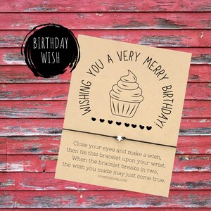 May include: A brown card with a white star charm bracelet. The card has a cupcake illustration and the text "Wishing you a very merry birthday!"  Close your eyes and make a wish, then tie this bracelet upon your wrist. When the bracelet breaks in two, the wish you made may just come true.  lovethejunk.com"
