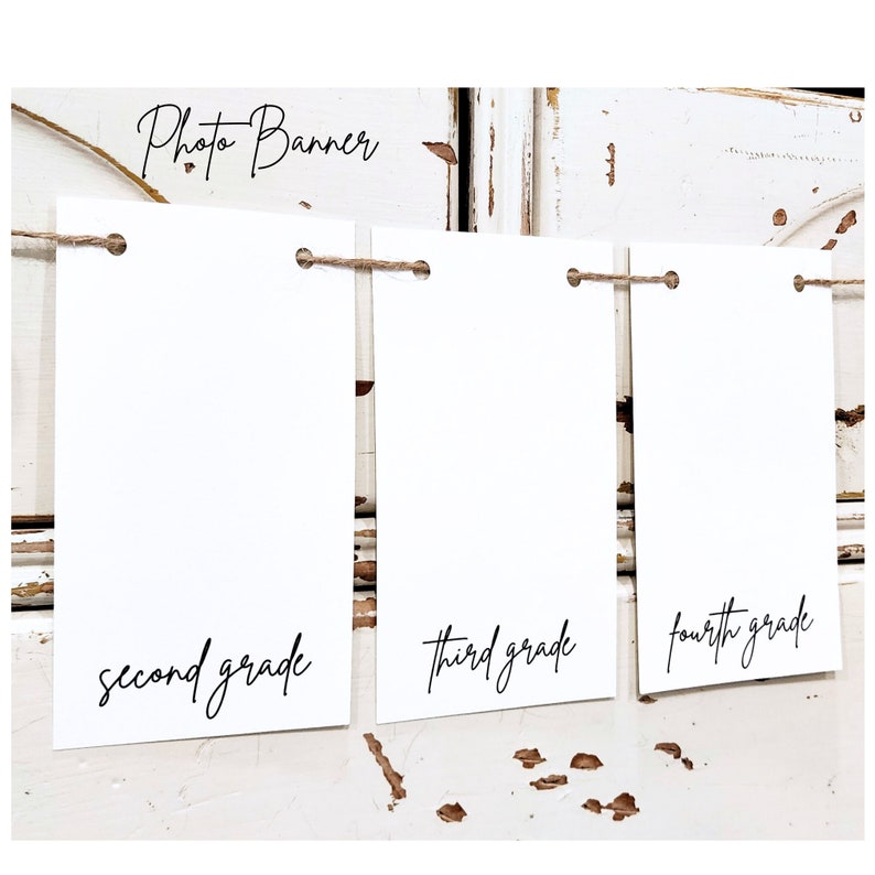 May include: Photo banner with three white cards strung together with twine. The cards have the words "second grade", "third grade", and "fourth grade" written on them in black cursive.