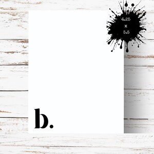 May include: A white rectangular card with the letter "b." in black at the bottom left corner. A black ink splatter with the text "4.25 x 5.5" is in the upper right corner. The background is a white wooden surface.