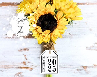 May include: A white gift tag with black text that reads "Congrats Class of 2025". The tag is tied to a bouquet of yellow sunflowers.