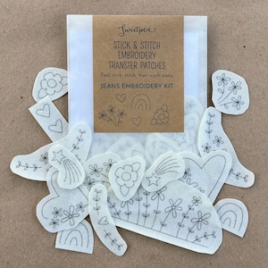 Peut inclure: Un ensemble de patchs de transfert de broderie en tissu blanc avec divers motifs, notamment des fleurs, des cœurs, des étoiles et des arcs-en-ciel. Les patchs font partie d'un "Kit de broderie pour jeans" et sont emballés avec une étiquette en papier brun.