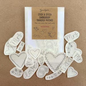 May include: A set of 15 white fabric patches featuring various wedding-themed designs, including hearts, rings, flowers, and the words "love" and "mrs". The patches are packaged in a clear plastic bag with a brown paper label that reads "Sweetpea Stick & Stitch Embroidery Transfer Patches".