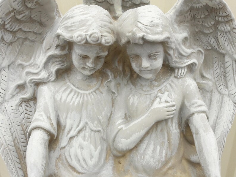 May include: Two white angel figurines with wings, one with long hair and the other with short hair, both with a serene expression.