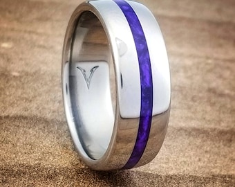 May include: A silver titanium ring with a purple inlay. The ring has a polished finish and a smooth surface.