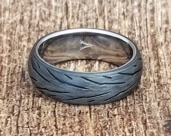 May include: A black and silver ring with a tire tread pattern. The ring is made of titanium and carbon fiber.