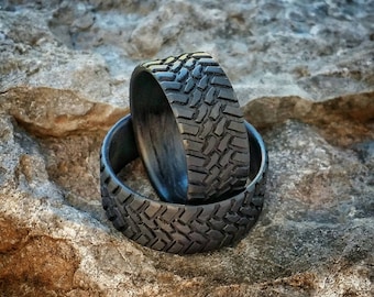 May include: Two black rubber rings with a tire tread pattern. The rings are stacked on top of each other.