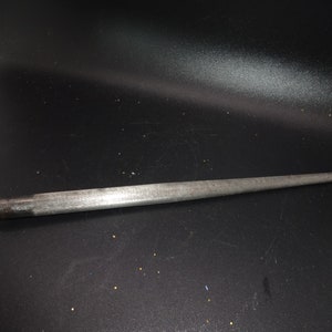 May include: A silver-toned metal object with a long, tapered point. The handle has a decorative, patterned design. The object appears to be a tool, possibly for sharpening or piercing.