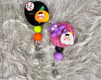 May include: Two Halloween themed retractable badge holders with colorful beads. One features a black and orange pumpkin and ghost, the other a purple bat and a white ghost with a witch's hat.