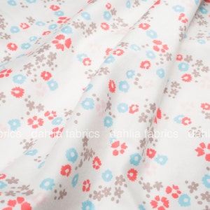 May include: White fabric with a repeating pattern of small blue, pink, and brown flowers.