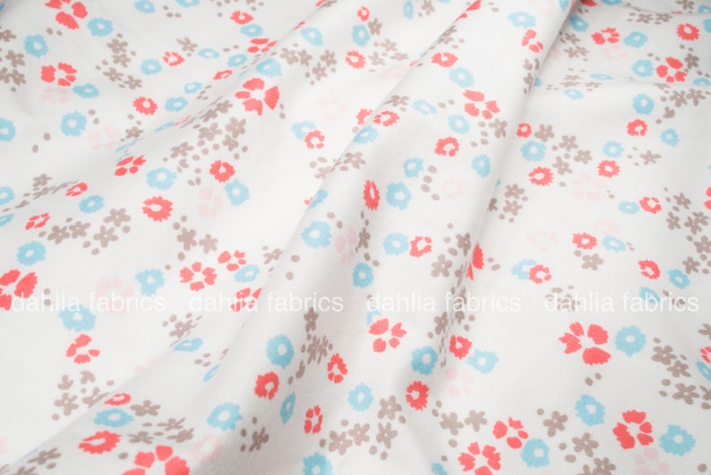 May include: White fabric with a repeating pattern of small blue, pink, and brown flowers.