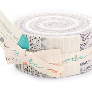 May include: A roll of fabric featuring a variety of white and gray prints with black accents. The fabric is rolled up and tied with a white ribbon. The label reads "Modern Background - Paper Zen Chic" and "moda".