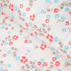 May include: White cotton fabric with a repeating pattern of small brown flowers, light blue flowers, and coral red flowers.