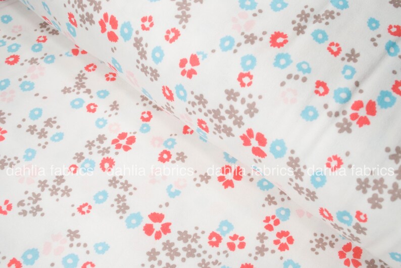 May include: White cotton fabric with a repeating pattern of small brown flowers, light blue flowers, and coral red flowers.