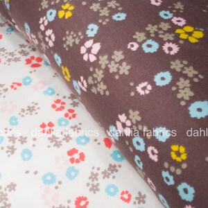 May include: Two fabric swatches with floral patterns. The top swatch is brown with a white, pink, and yellow floral pattern. The bottom swatch is white with a light blue, pink, and red floral pattern.