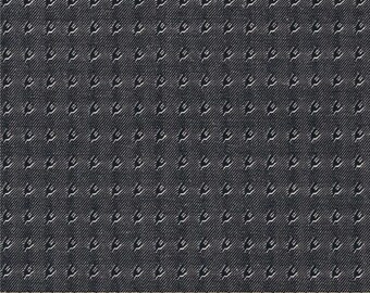 May include: Dark blue fabric with a repeating white pattern. The pattern consists of small, stylized, curved shapes. The fabric has a textured appearance, with diagonal lines visible throughout. A wooden ruler is at the bottom, showing inch measurements.