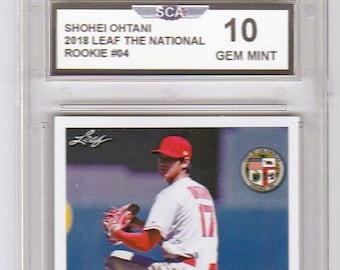 May include: A baseball card featuring a baseball player in a red and white uniform, holding a baseball glove. The card is graded 10 Gem Mint by SCA. The card features the text "Shohei Ohtani 2018 Leaf The National Rookie #04" and "Shohei Ohtani".