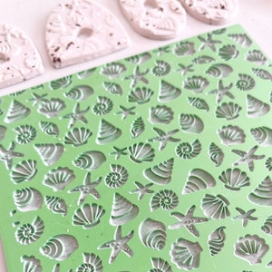 May include: Green silicone mould with various seashell and starfish designs. The mould is used for creating decorative items.