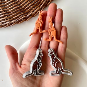 May include: Two sets of kangaroo cookie cutters. One set is orange and the other is silver.