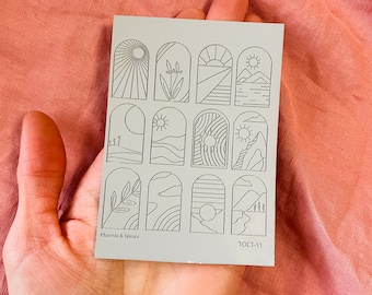 May include: A sheet of 12 nail art stickers with various arch designs featuring nature scenes, including sun, mountains, clouds, and plants. The stickers are printed on a light gray background and have the text "Phoenix & Spruce" and "10CT-11" printed on the bottom.