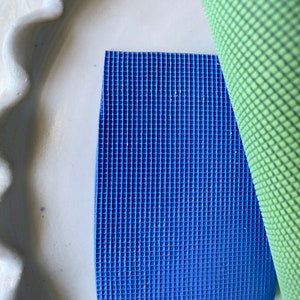 Pode incluir: Um tapete de ioga azul e verde com uma superfície texturizada. O tapete é feito de um material macio e flexível, ideal para ioga, pilates ou alongamento.