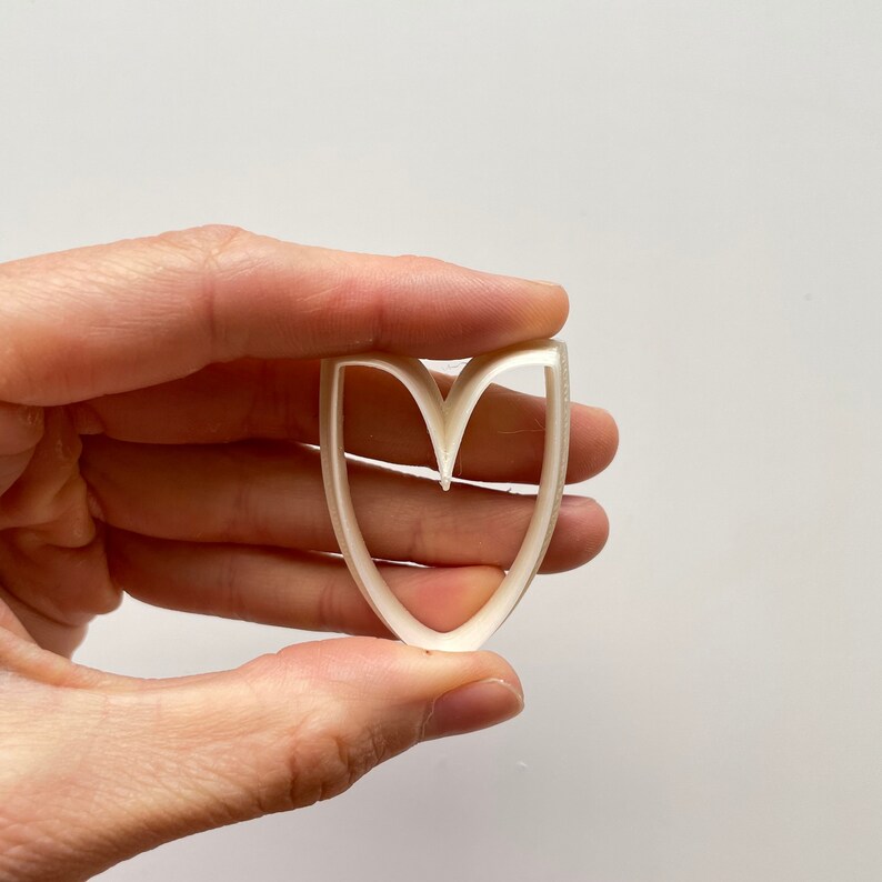 May include: White plastic heart-shaped cookie cutter with a double layer design.
