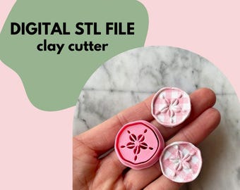 May include: A hand holds three clay cutters. One is bright pink with a floral design, and the other two are white and pink gingham with a floral design. The text "DIGITAL STL FILE clay cutter" is in the background.