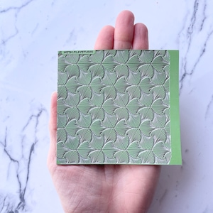 May include: A green polymer clay texture sheet with a repeating pattern of stylized ginkgo leaves. The sheet is labeled "METALCLAYSTUDIO".