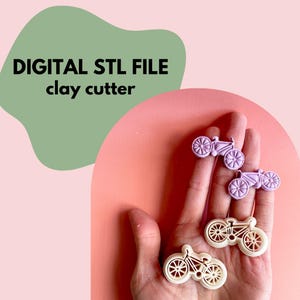 May include: The image shows three bicycle-shaped clay cutters in shades of purple and cream. The text "DIGITAL STL FILE clay cutter" is displayed in black. The cutters are held in a hand against a pink and green background.
