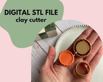 May include: The image displays three clay cutters in a hand, with the text "DIGITAL STL FILE clay cutter" in black. One cutter is orange, and the other two are tan. The cutters are circular with decorative edges. The background is a light pink and green.