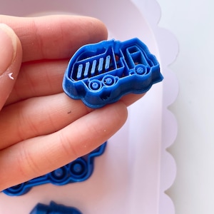 May include: Blue plastic cookie cutters shaped like a garbage truck. The cutters are designed to cut out shapes from dough or fondant.