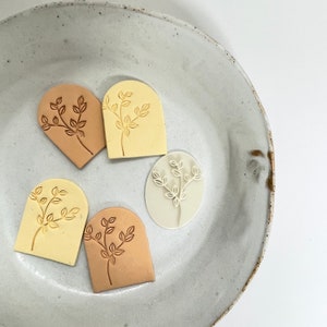 May include: Four different shaped rubber stamps with a leaf design. The stamps are in various shades of brown and cream.