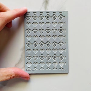May include: A grey silicone stencil with a repeating pattern of pixelated hearts. The stencil is labelled "Phoenix & Spice" and "TOCT-5".