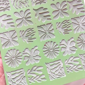 Op de afbeelding: Een groene siliconen stempelplaat met verschillende bloem- en bladontwerpen. De plaat is getextureerd en heeft een lichtgroene kleur.