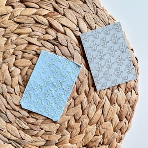 May include: Two light blue cards with a repeating pattern of stylized birds. The cards are on a woven straw mat.