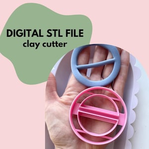 May include: Two clay cutters, one light blue and one pink, held in a hand. The cutters are circular with a crossbar design. The text "DIGITAL STL FILE clay cutter" is in the upper left corner against a green background.