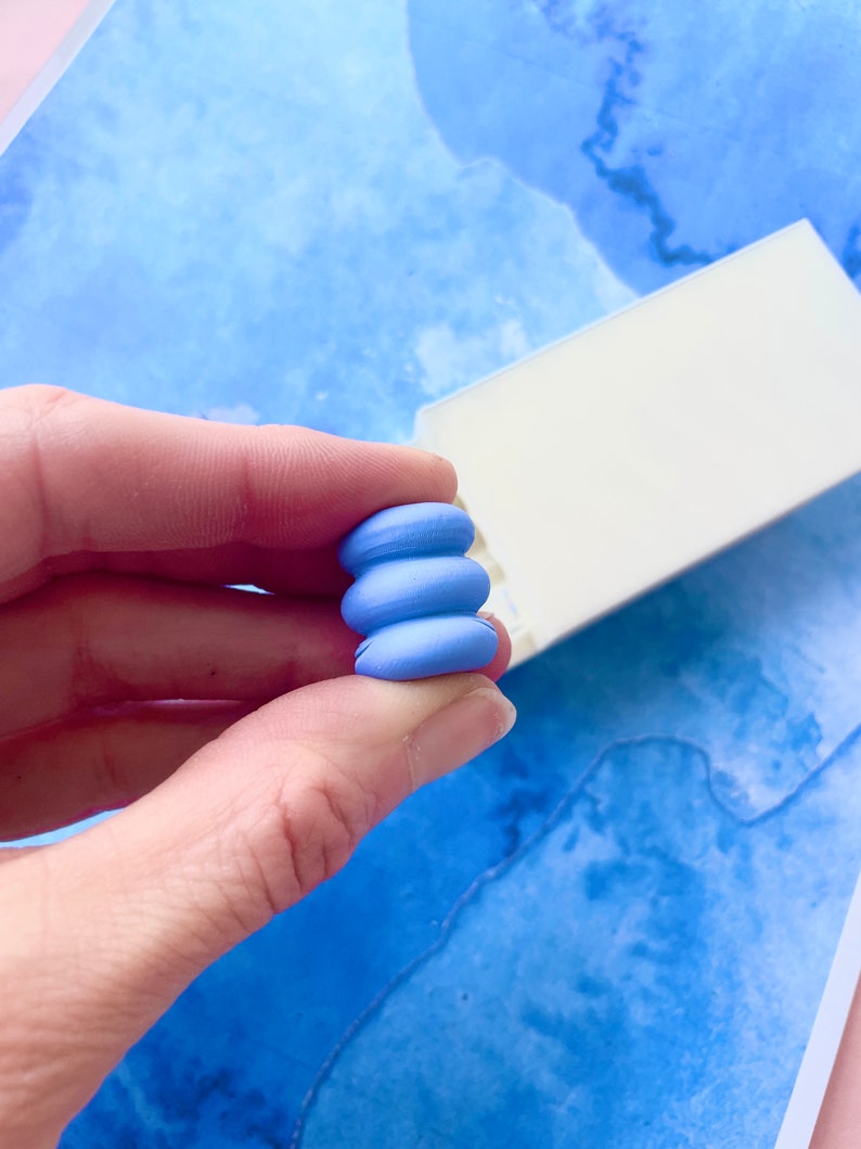 May include: A stack of three blue polymer clay beads, each with a slightly different shape, creating a unique and modern design.
