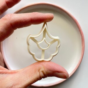 May include: White plastic cookie cutter shaped like a flower with a detailed design.