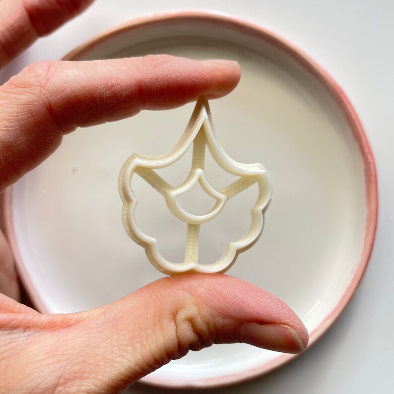 May include: White plastic cookie cutter shaped like a flower with a detailed design.