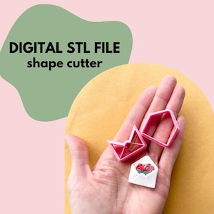 May include: Three pink plastic cookie cutters in the shape of envelopes. The cutters are held in a hand against a yellow background. The text "DIGITAL STL FILE shape cutter" is visible in the top left corner of the image.