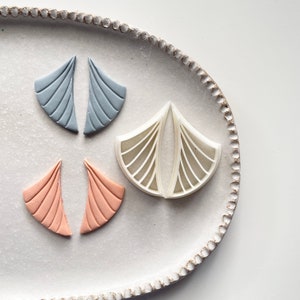 Könnte beinhalten: Drei Paare geometrisch geformter Ohrringe in einer weißen Keramik Schale. Die Ohrringe sind aus Polymer Clay und in den Farben Hellblau, Hellrosa und Weiß.