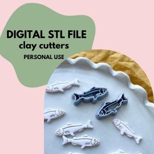 Może przedstawiać: Białe i szare wycinaki do gliny w kształcie ryb ułożone na białym talerzu. Obraz zawiera tekst "DIGITAL STL FILE clay cutters PERSONAL USE" czarnymi literami na zielono-różowym tle. Wycinaki są do użytku osobistego.