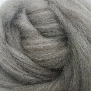 May include: A close-up of a pile of gray wool roving. The wool is soft and fluffy, and it is perfect for felting or spinning.