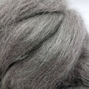 以下が含まれることがあります： グレーのウールロービングの束のクローズアップ。ウールは柔らかくふわふわで、紡績やフェルトに最適です。