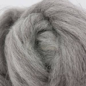 May include: A close-up of a bundle of gray wool roving. The wool is soft and fluffy, and it is perfect for spinning or felting.