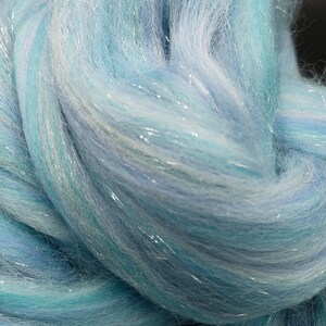 K&ouml;nnte beinhalten: Nahaufnahme eines B&uuml;ndels aus hellblauem und wei&szlig;em Garn mit durchg&auml;ngig eingewebten silbernen Glitzerf&auml;den.