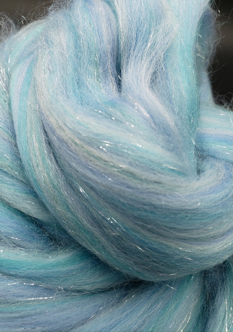 K&ouml;nnte beinhalten: Nahaufnahme eines B&uuml;ndels aus hellblauem und wei&szlig;em Garn mit durchg&auml;ngig eingewebten silbernen Glitzerf&auml;den.