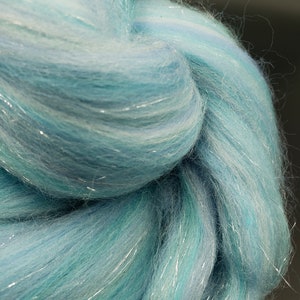 K&ouml;nnte beinhalten: Nahaufnahme eines B&uuml;ndels hellblauer und wei&szlig;er Wolle mit silbernen Glitzerf&auml;den, die durch die gesamte Wolle gewebt sind.