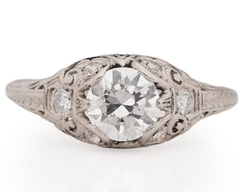 May include: A silver engagement ring with a large round diamond center stone and smaller diamonds on the band.
