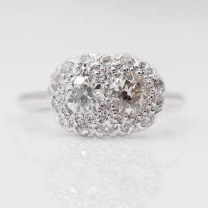 Può includere: Un anello d'argento con un grande diamante di forma ovale circondato da diamanti più piccoli.